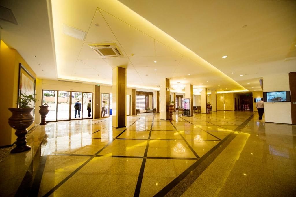 A spacious lobby with a polished floor, large columns, and a reception desk.