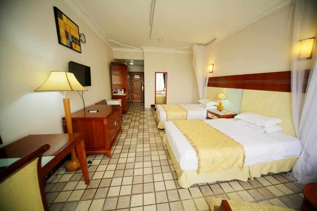 Une chambre d’hôtel avec deux lits, un bureau, une chaise, une télévision et un miroir.
