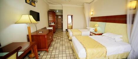 A hotel room with two beds, a desk, a chair, a television, and a mirror.
