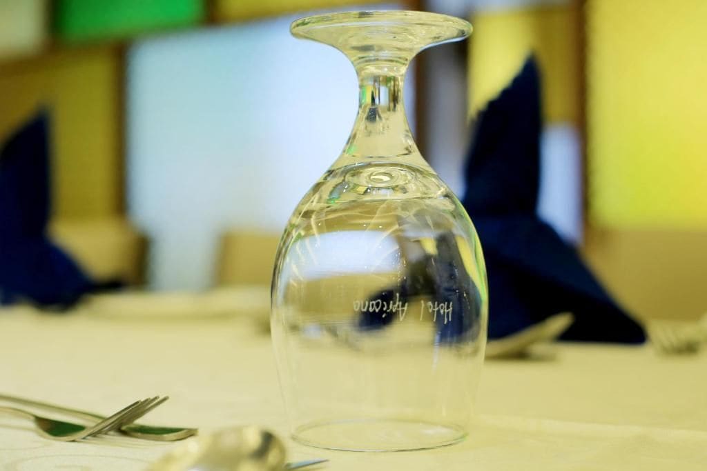 Une bouteille en verre transparent, à col étroit et à base plus large, posée sur une table, avec un arrière-plan flou.