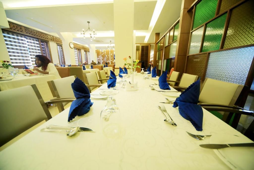 A restaurant with tables set for dining, featuring blue napkins and clear glassware.