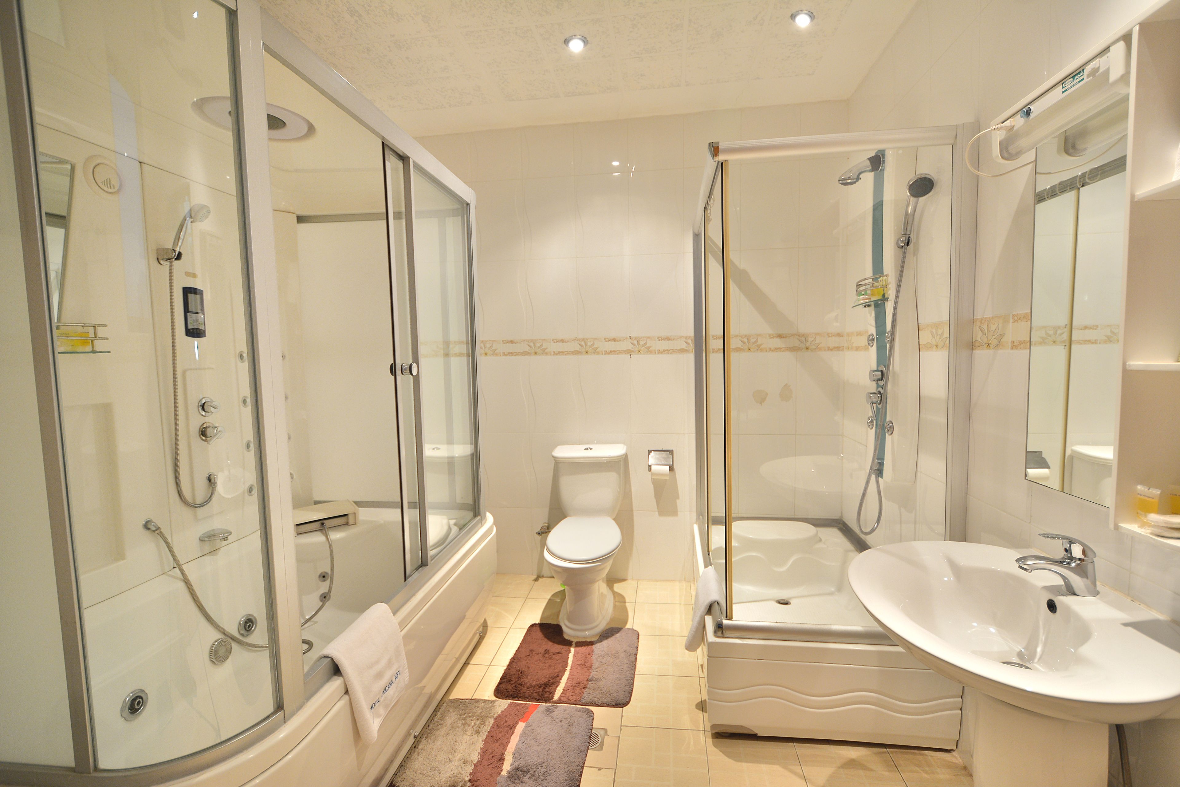 A modern bathroom with a glass-enclosed shower, a standalone toilet, a freestanding bathtub, and a white sink.