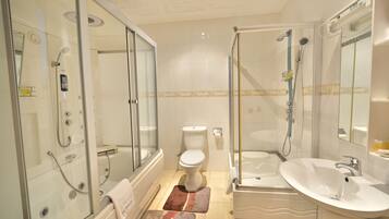 A modern bathroom with a glass-enclosed shower, a standalone toilet, a freestanding bathtub, and a white sink.