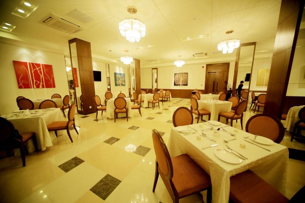 A hotel dining area with multiple tables and chairs, a polished floor, and artwork on the walls.