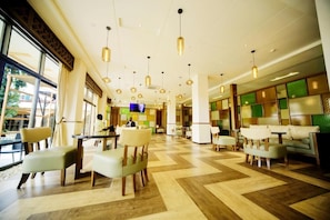 A hotel lobby with a check-in counter, seating area, and large windows. - Hotel Africana (Kampala)