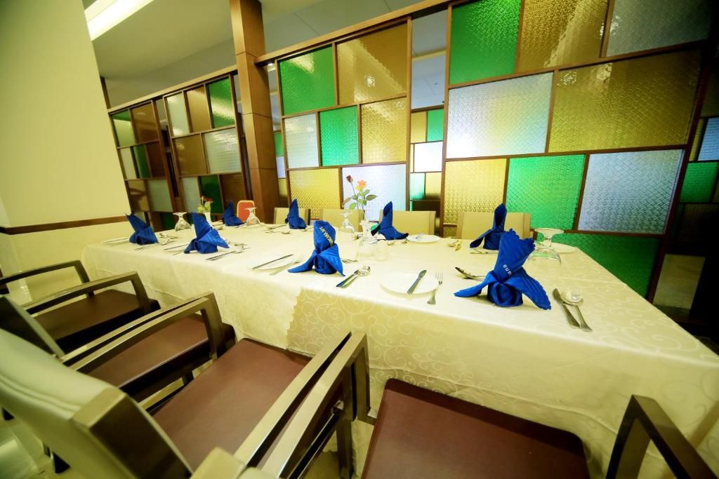 A dining area with a long table set for a meal, chairs around the table, and a decorative wall with green and beige panels.