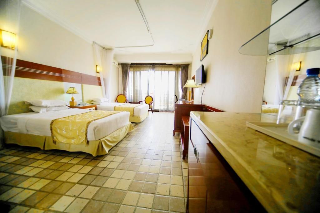 Habitación de hotel con dos camas, un escritorio, una silla, un televisor y un espejo de baño.