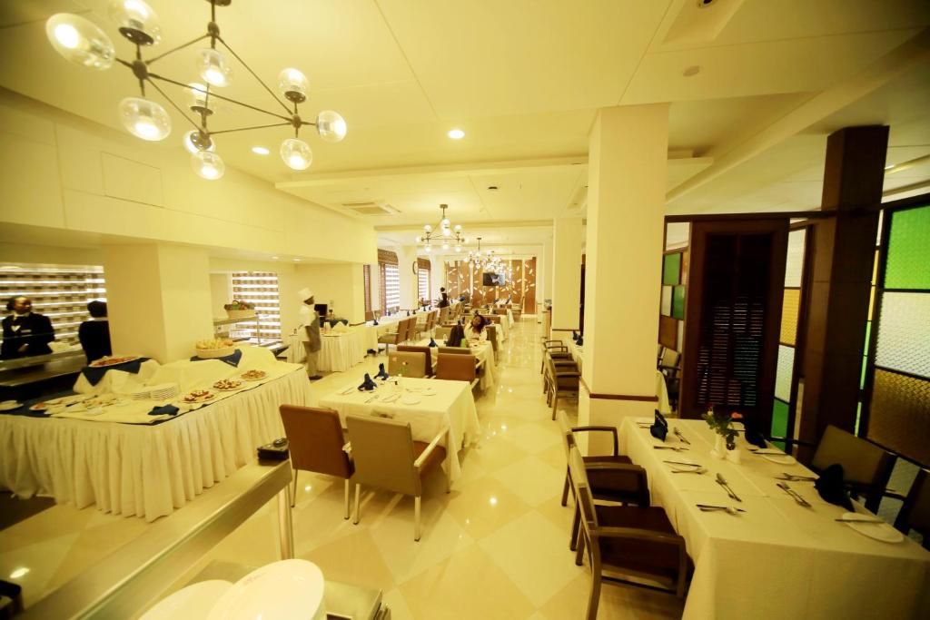 A spacious dining area with multiple tables and chairs, a buffet setup on the left, and a long counter with a chef.