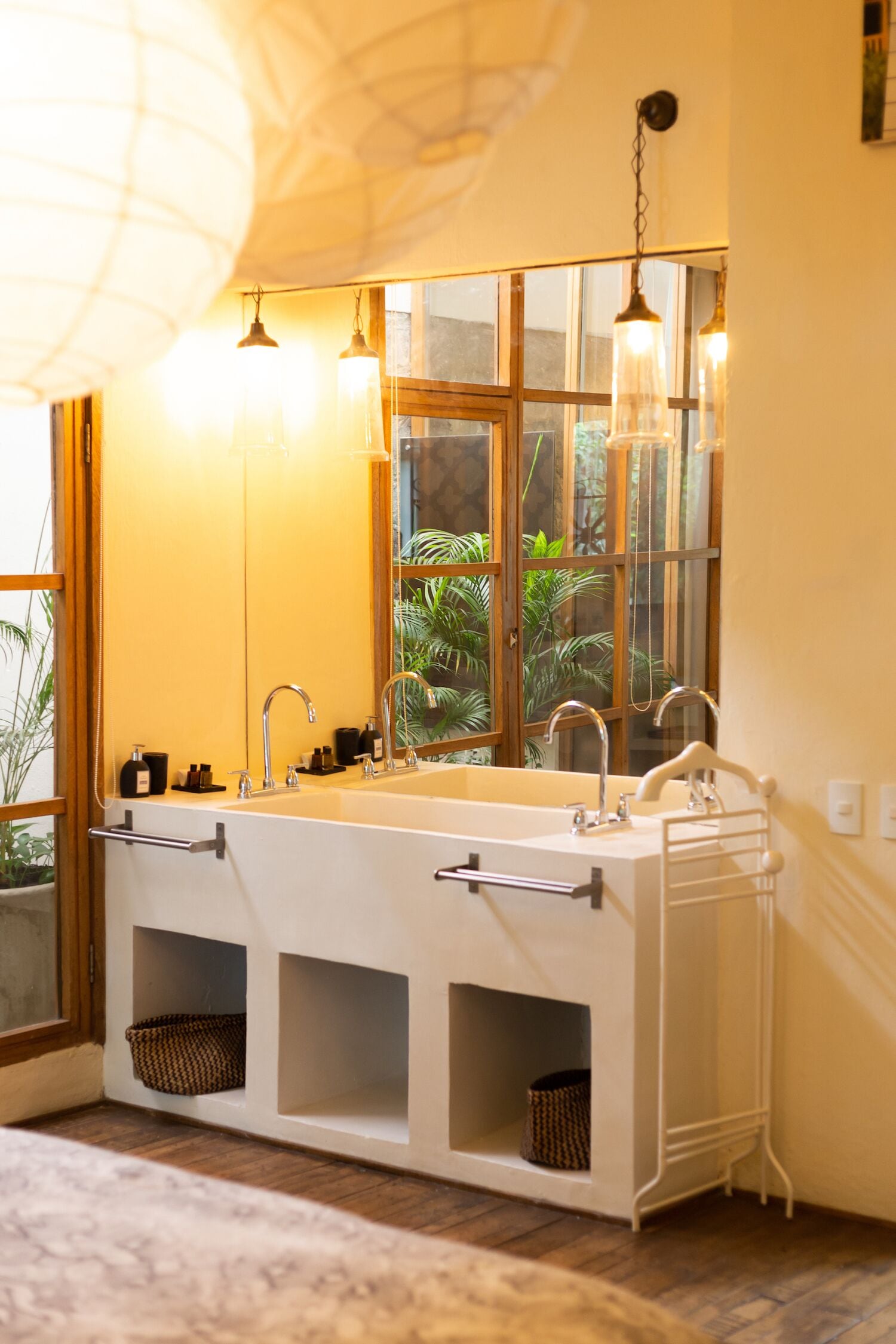 Ein Badezimmer mit großem Fenster, zwei Waschbecken und hängenden Pendelleuchten.