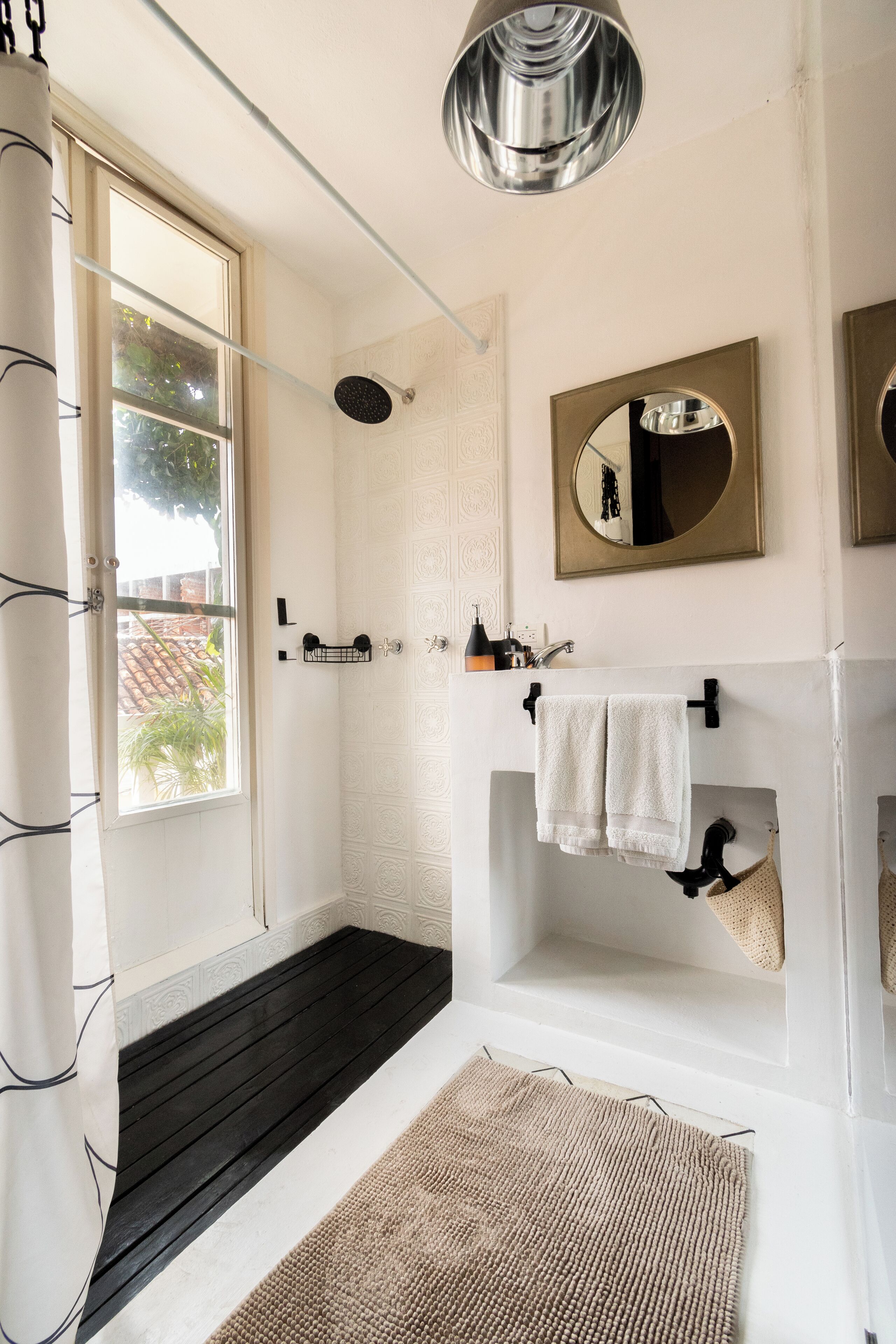 A modern bathroom with a shower, a sink, a mirror, and a towel rack.