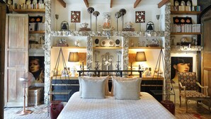 Een ruime slaapkamer met een groot bed, een houten plafond en een boekenplank vol boeken.