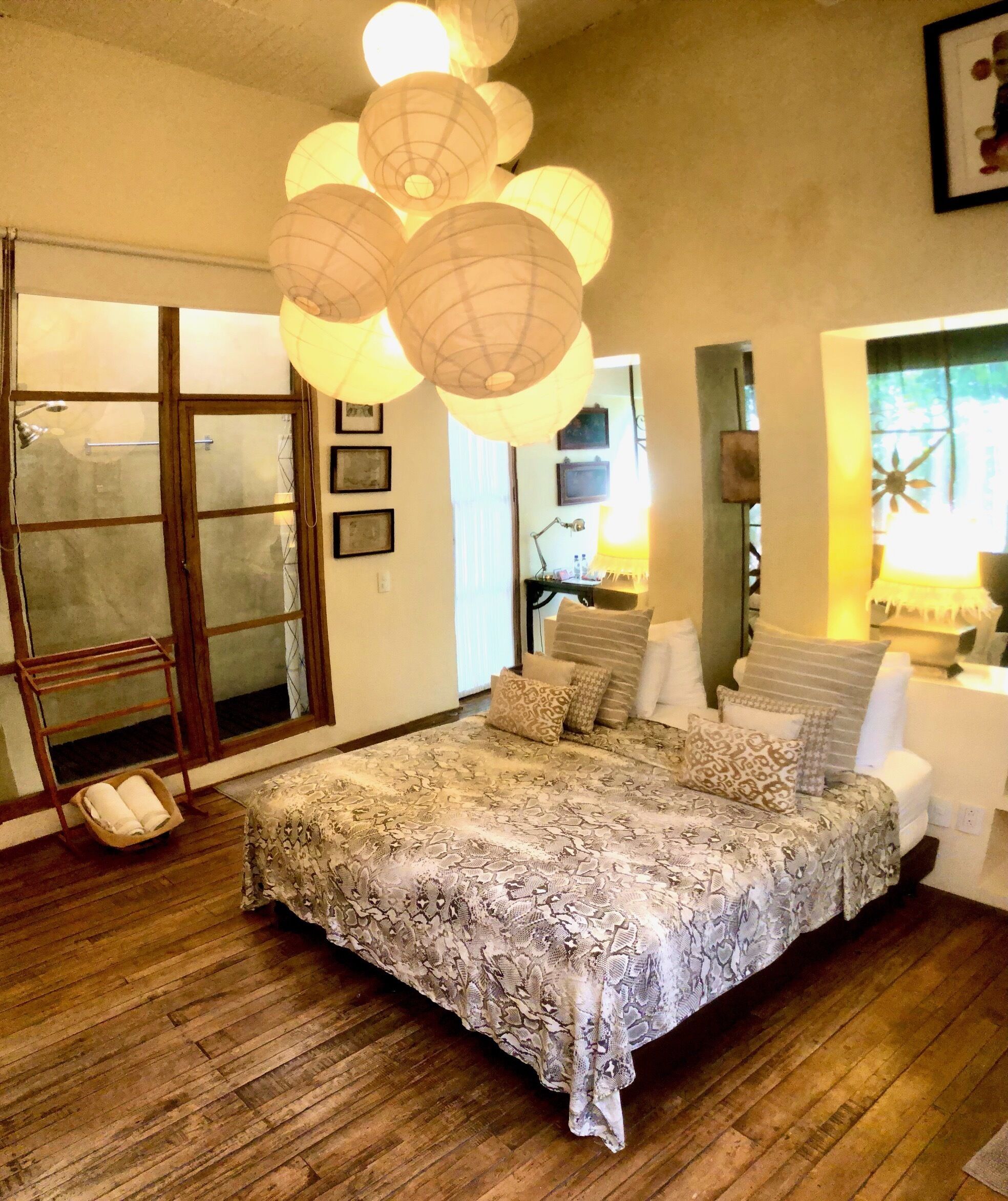 A bedroom with a large bed, wooden flooring, and a large window.