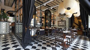 Een restaurant met een schachootjes vloer, zwart-wit hanglampen en ingelijste foto’s aan de muren.