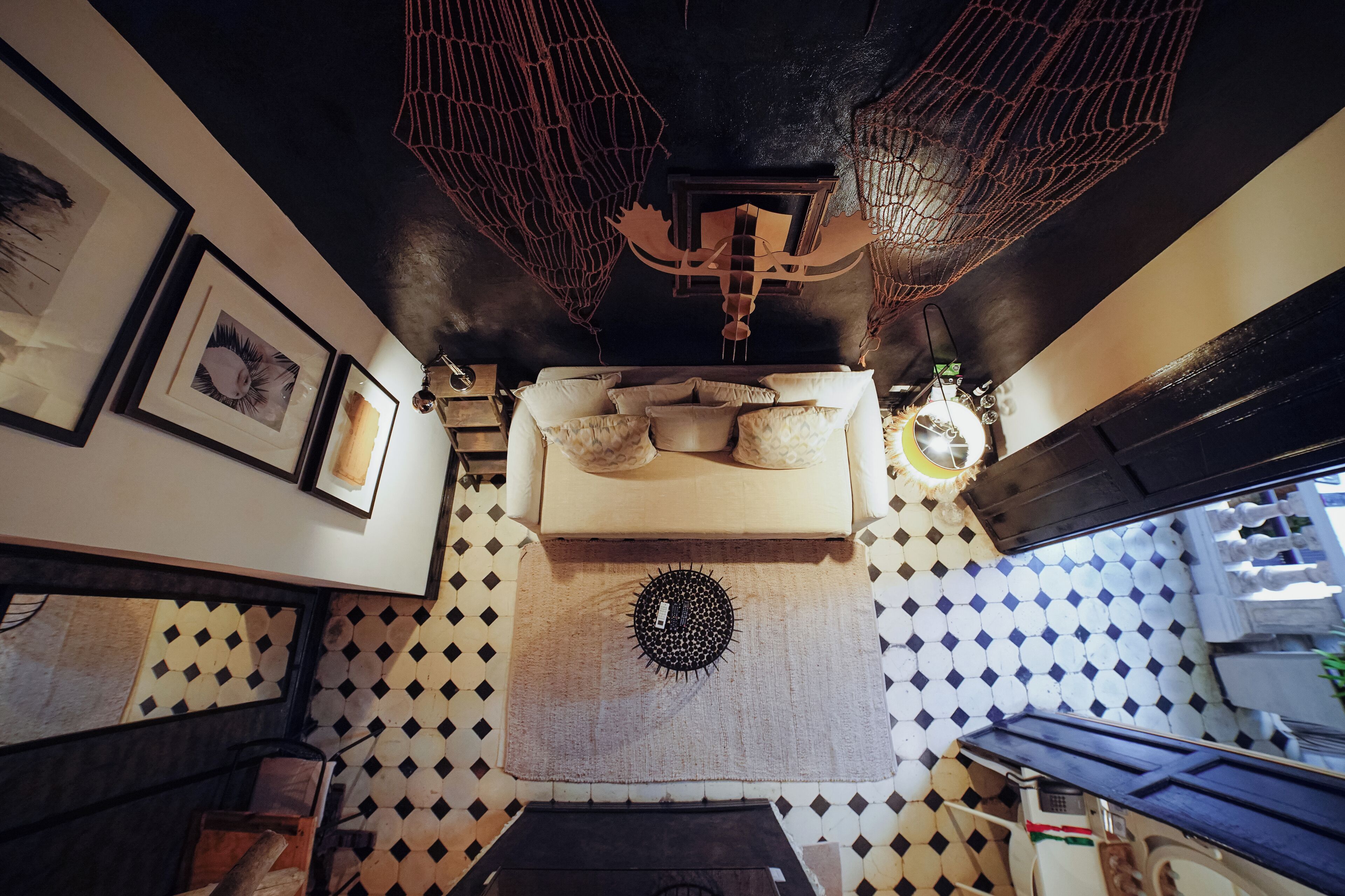 Una habitación con piso estampado, una cama con almohadas, un adorno en la pared y una lámpara en el techo.