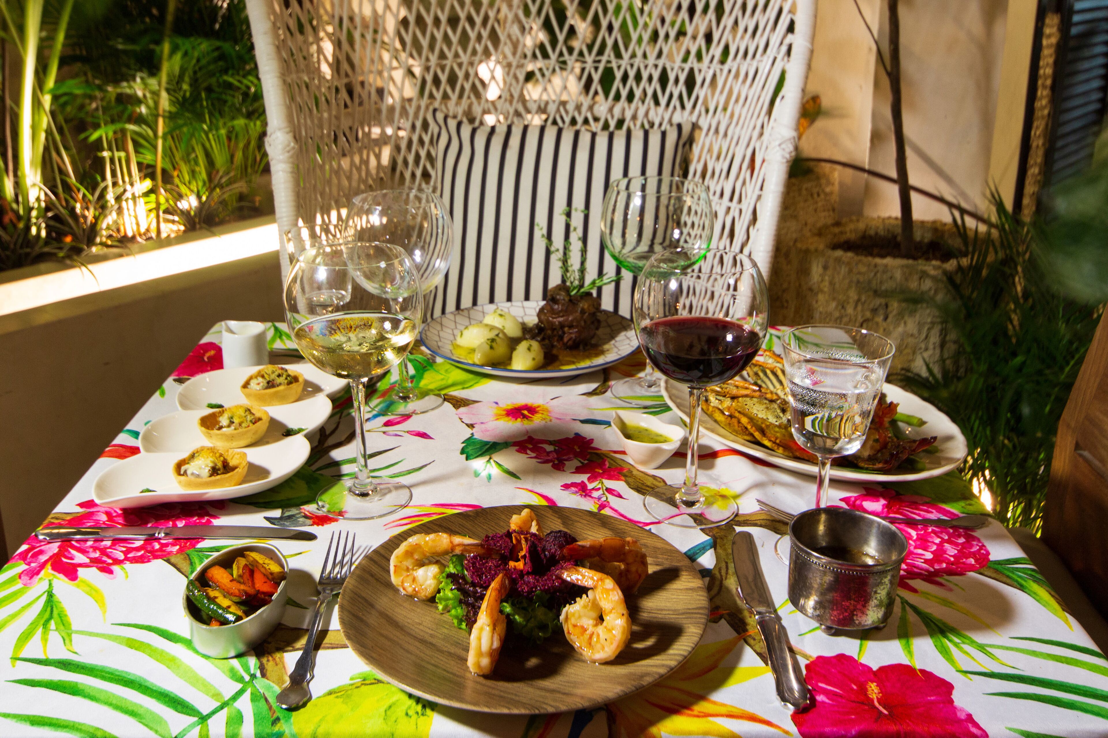 A table set with plates of food, wine glasses, and cutlery.