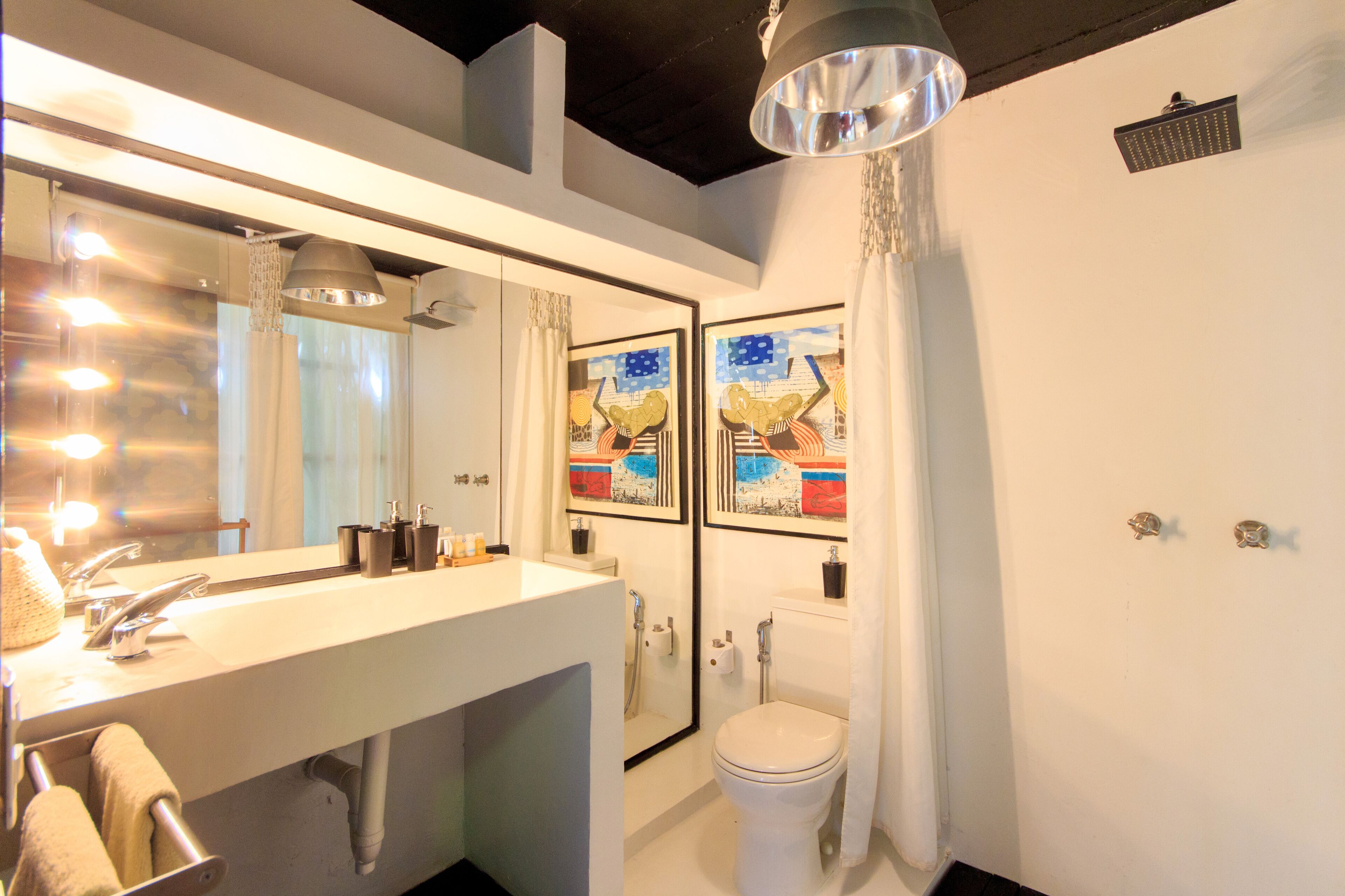 A bathroom with a large mirror, a sink, a toilet, and a shower.