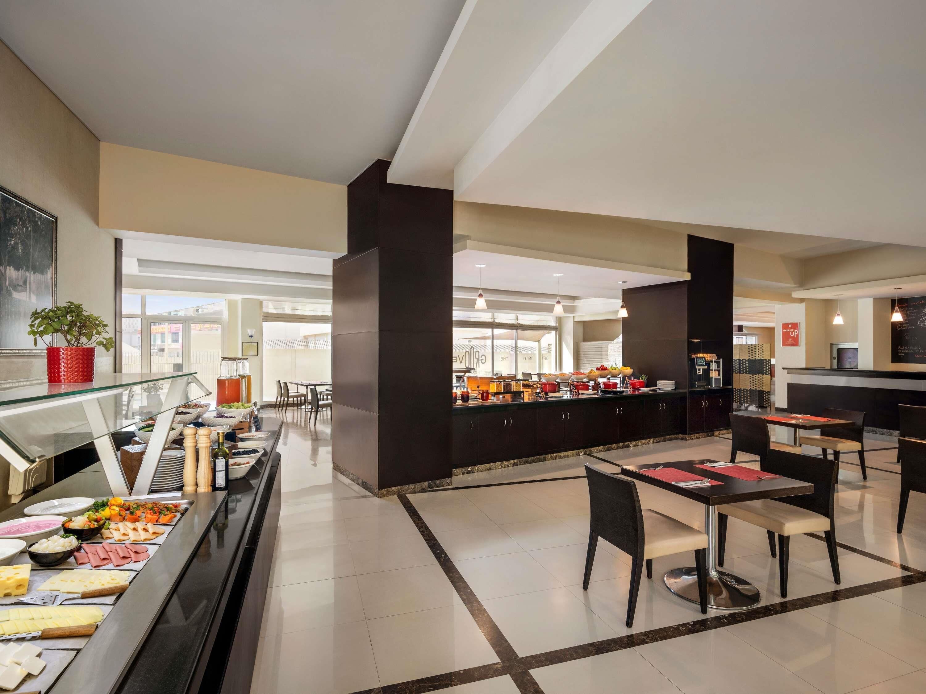 A buffet area with a variety of food items, a glass dining table, and a seating area with chairs.