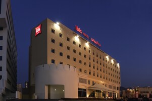 A hotel with a prominent "ibis" sign, multiple floors, and a modern architectural design.