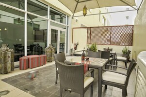 An outdoor patio area with wicker furniture, a glass door leading inside, and a decorative fence.