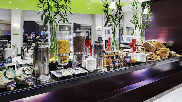 Un espace buffet proposant une variété de plats, notamment des options sans gluten et des céréales soufflées au riz, ainsi que des plantes décoratives en bambou.