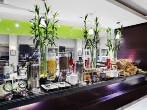 A buffet area with various food options, including gluten-free and rice crispy cereals, and decorative bamboo plants.