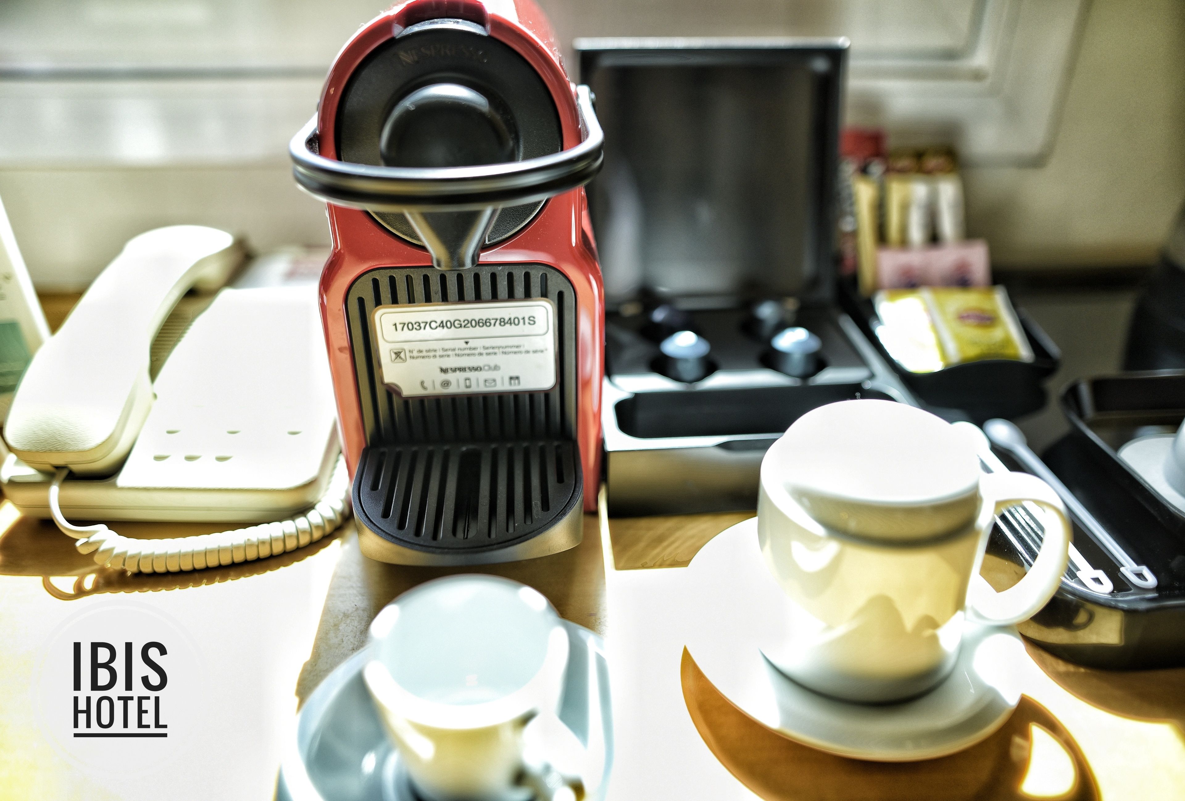 A kitchenette with a coffee maker, a phone, a cup, and a tea set.