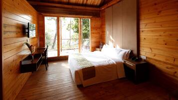 A wooden cabin bedroom with a bed, bedside table, and a desk with a chair.