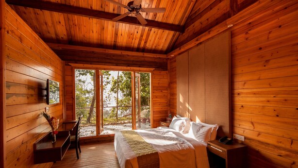 Un dormitorio de cabaña de madera con cama, mesita de noche y ventilador de techo.