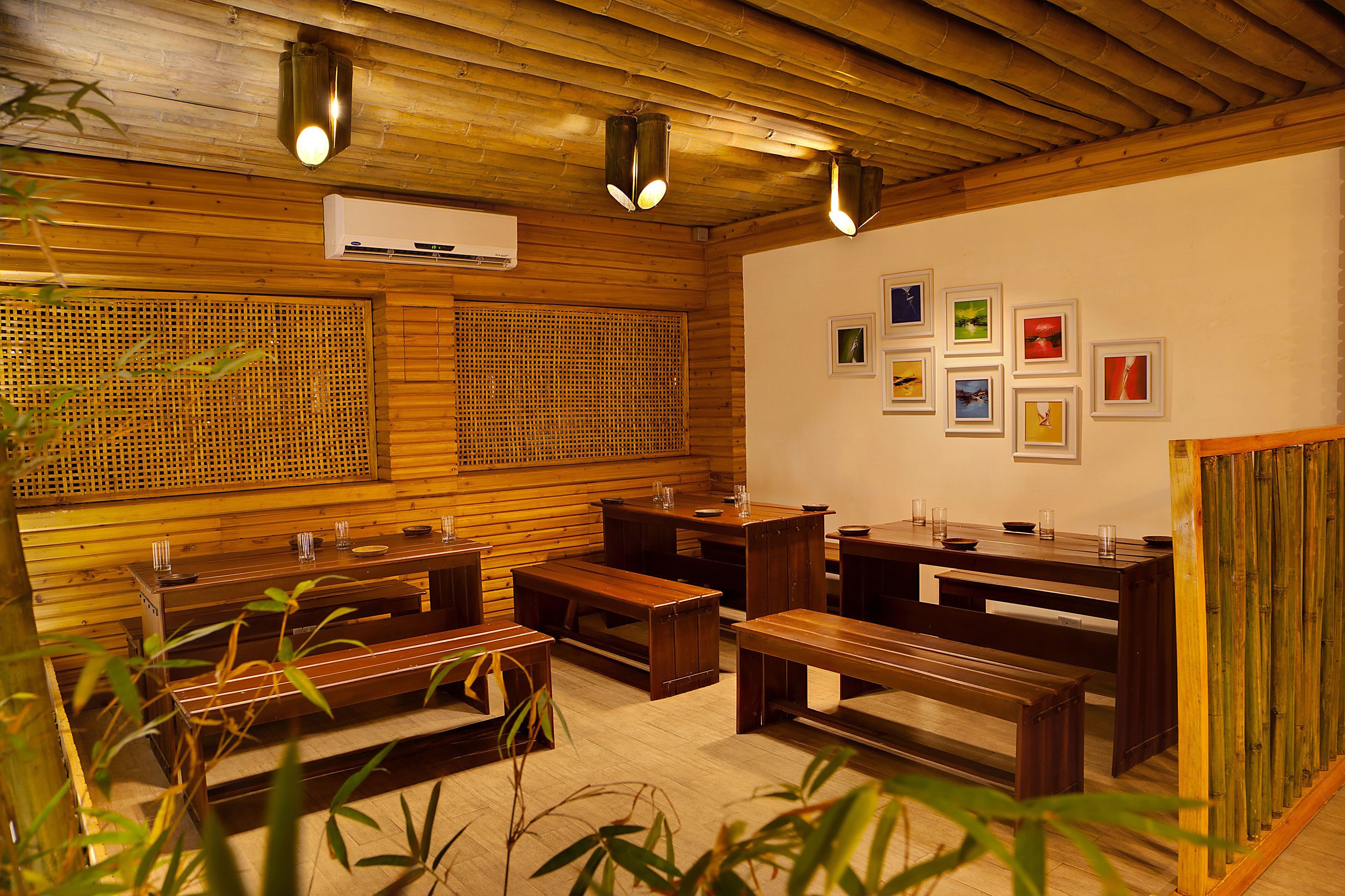 A wooden interior with benches and tables, air conditioning, and framed pictures on the wall.