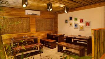 A wooden interior with benches and tables, air conditioning, and framed pictures on the wall.