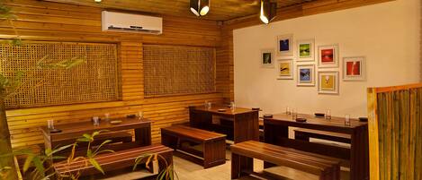 A wooden interior with benches and tables, air conditioning, and framed pictures on the wall.
