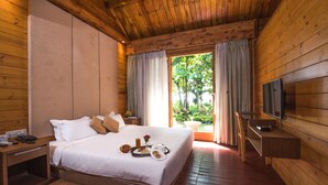 Un dormitorio de estilo cabaña con cama, mesita de noche, televisor y ventana con cortinas.