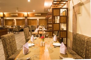 Un comedor con mesas dispuestas para una comida, sillas y una pared decorativa.