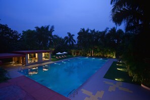 Una piscina con una casa moderna al fondo, rodeada de palmeras.