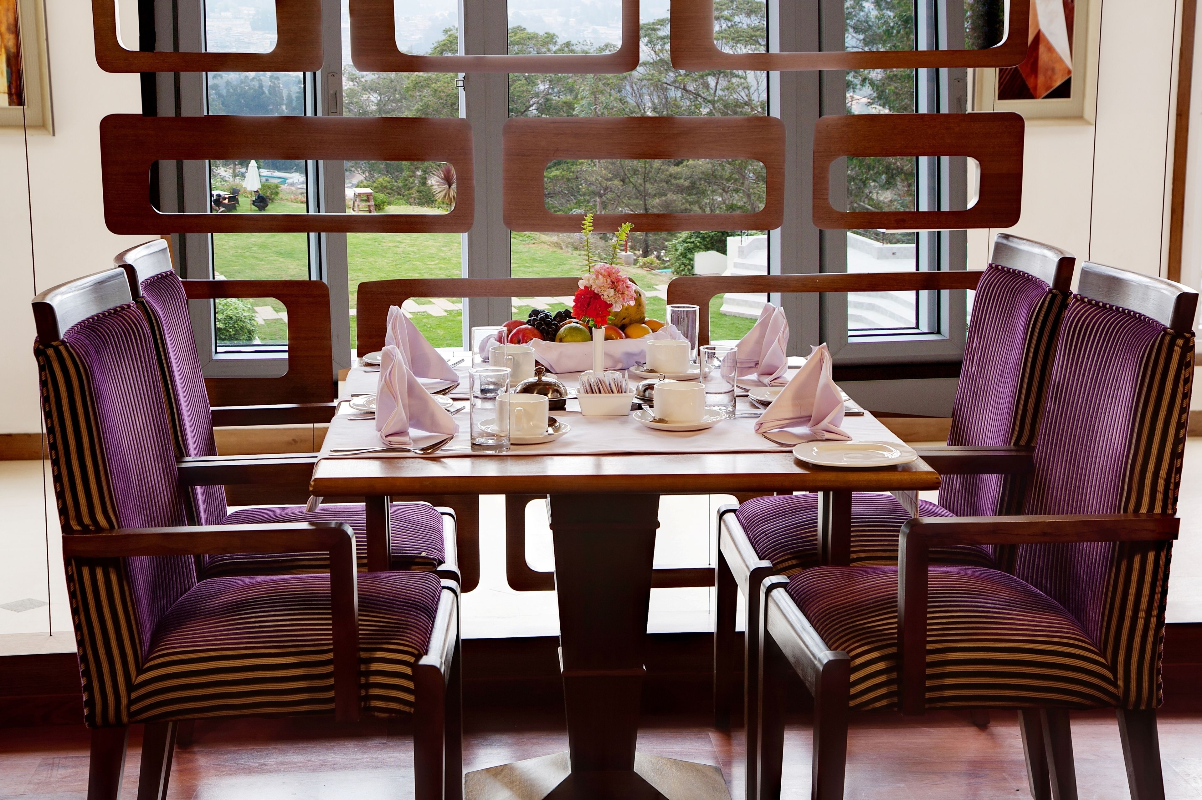 A dining area with a table set for four, surrounded by chairs with striped upholstery.