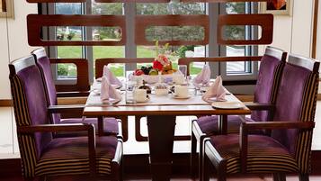 A dining area with a table set for four, surrounded by chairs with striped upholstery.