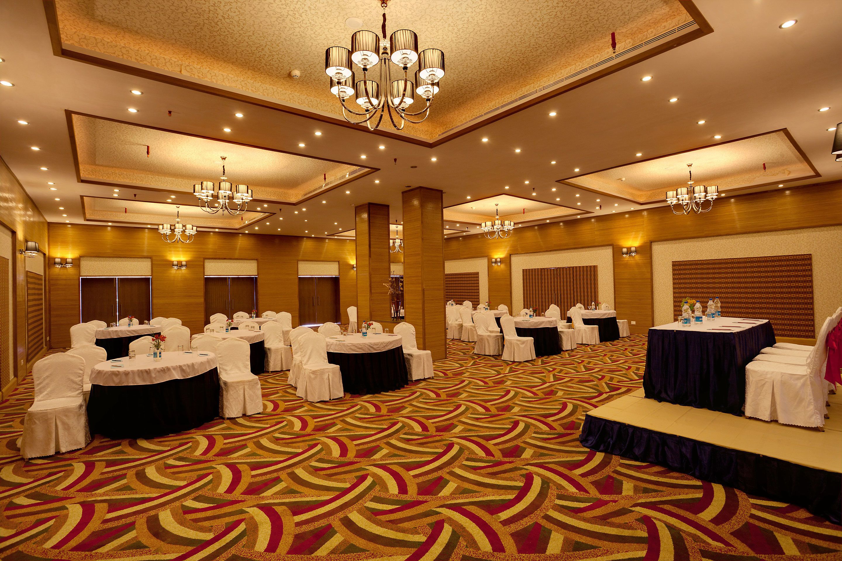 A large conference room with round tables, white chairs, and a stage.