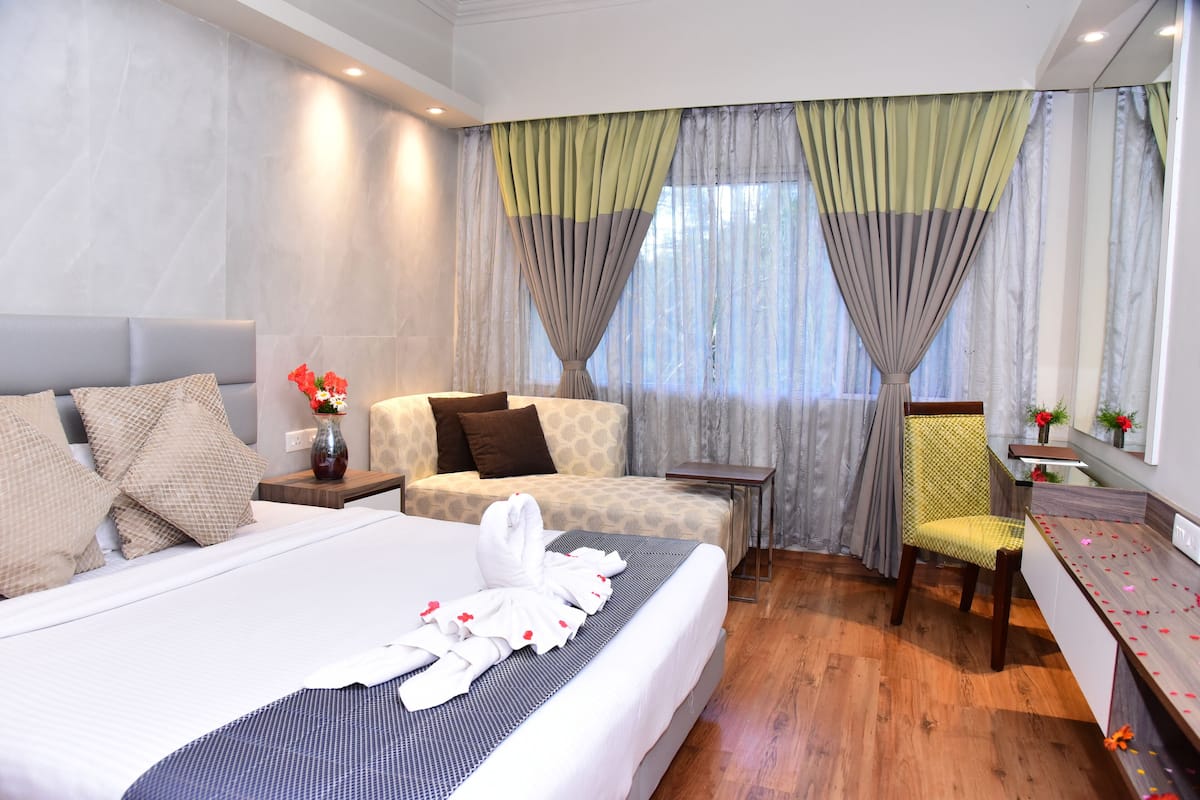 Una habitación de hotel con una cama grande, un sofá, una silla y una mesita.