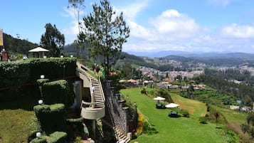 A landscaped garden with a spiral staircase, a gazebo, and a view of a town in the distance.