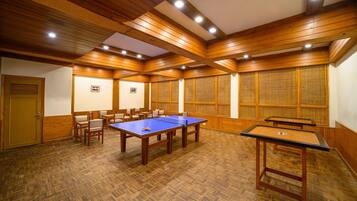 A room with wooden paneling, a ping pong table, and several chairs.