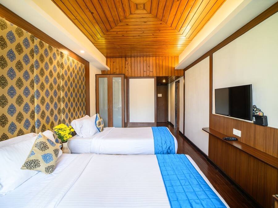 A hotel room with two beds, a TV, and a wooden ceiling.