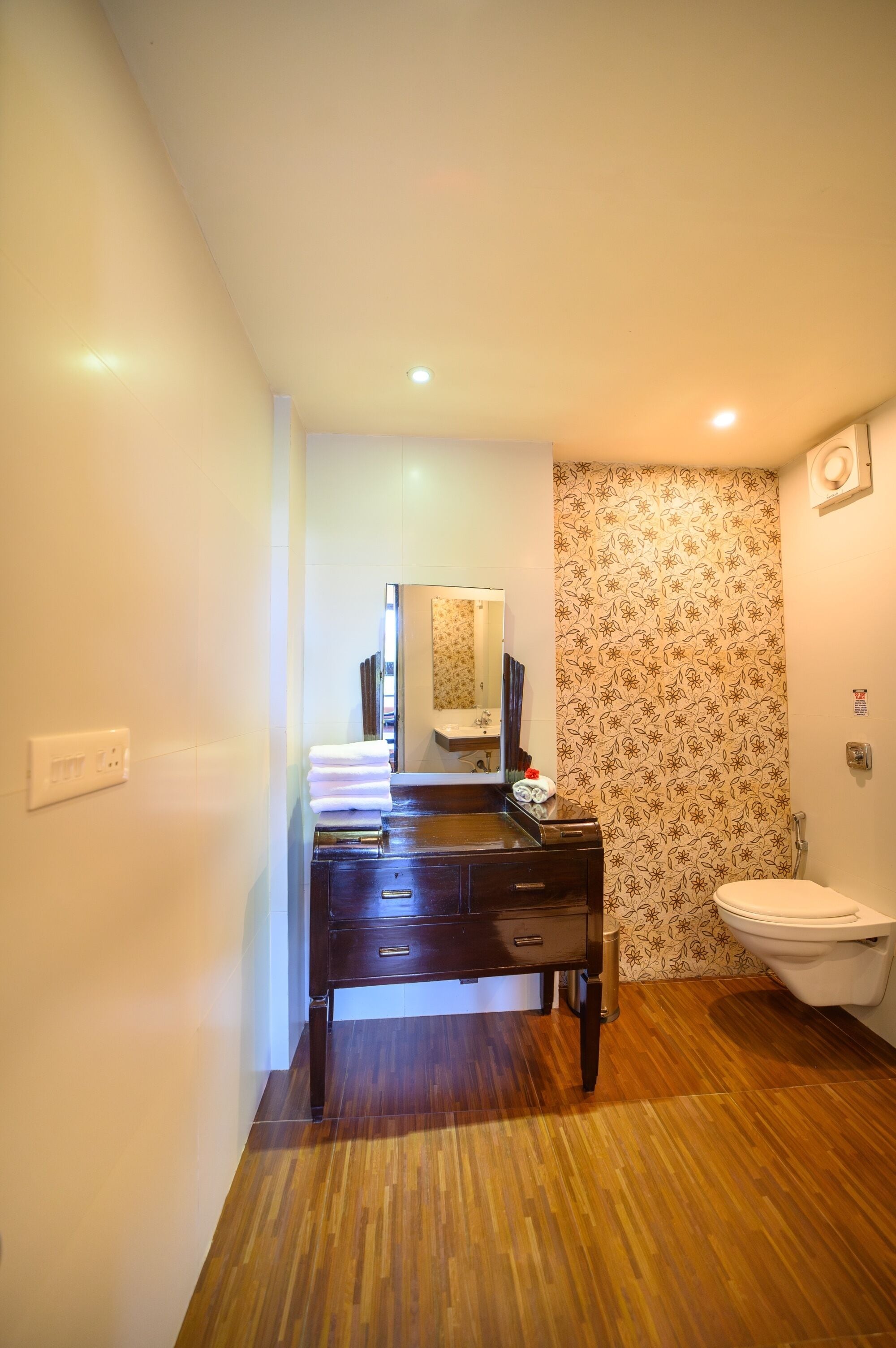 A bathroom with a wooden vanity, a toilet, and a mirror.