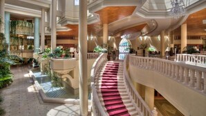 Eine prachtvolle Hotelhalle mit einer zentralen Treppe, mehreren Ebenen und einem geräumigen Atrium mit Pflanzen.