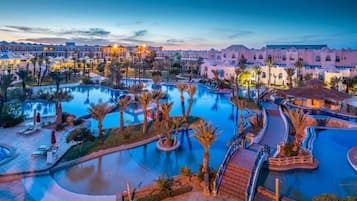 Relax by the resort's central pool surrounded by palm trees and lounge areas.