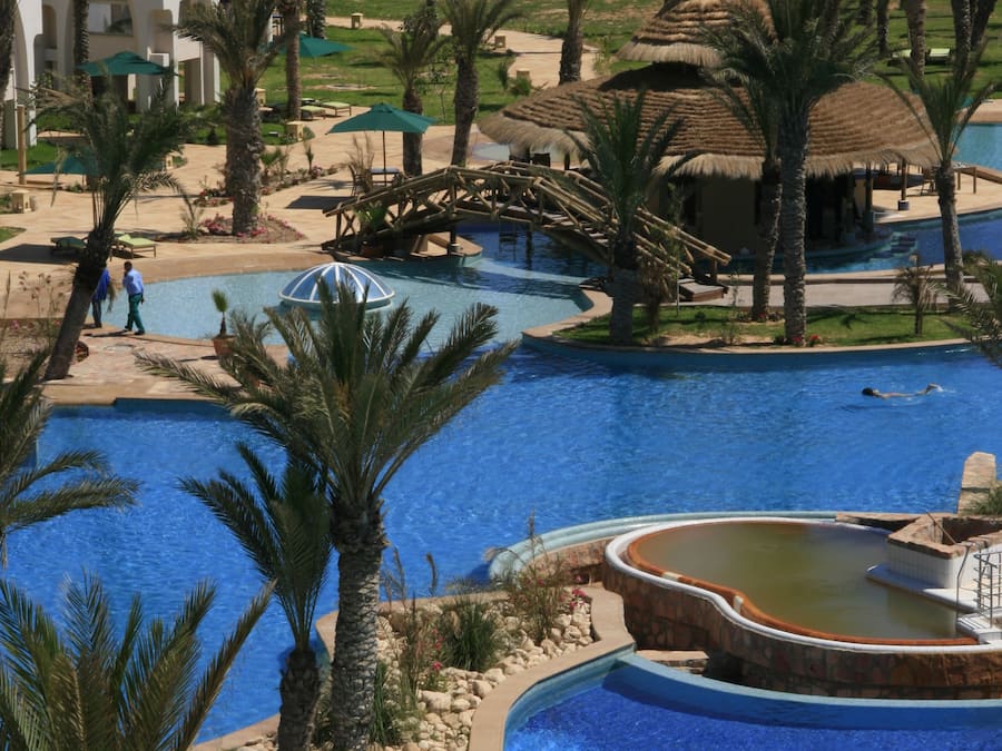 Una piscina techada, una piscina al aire libre, sombrillas