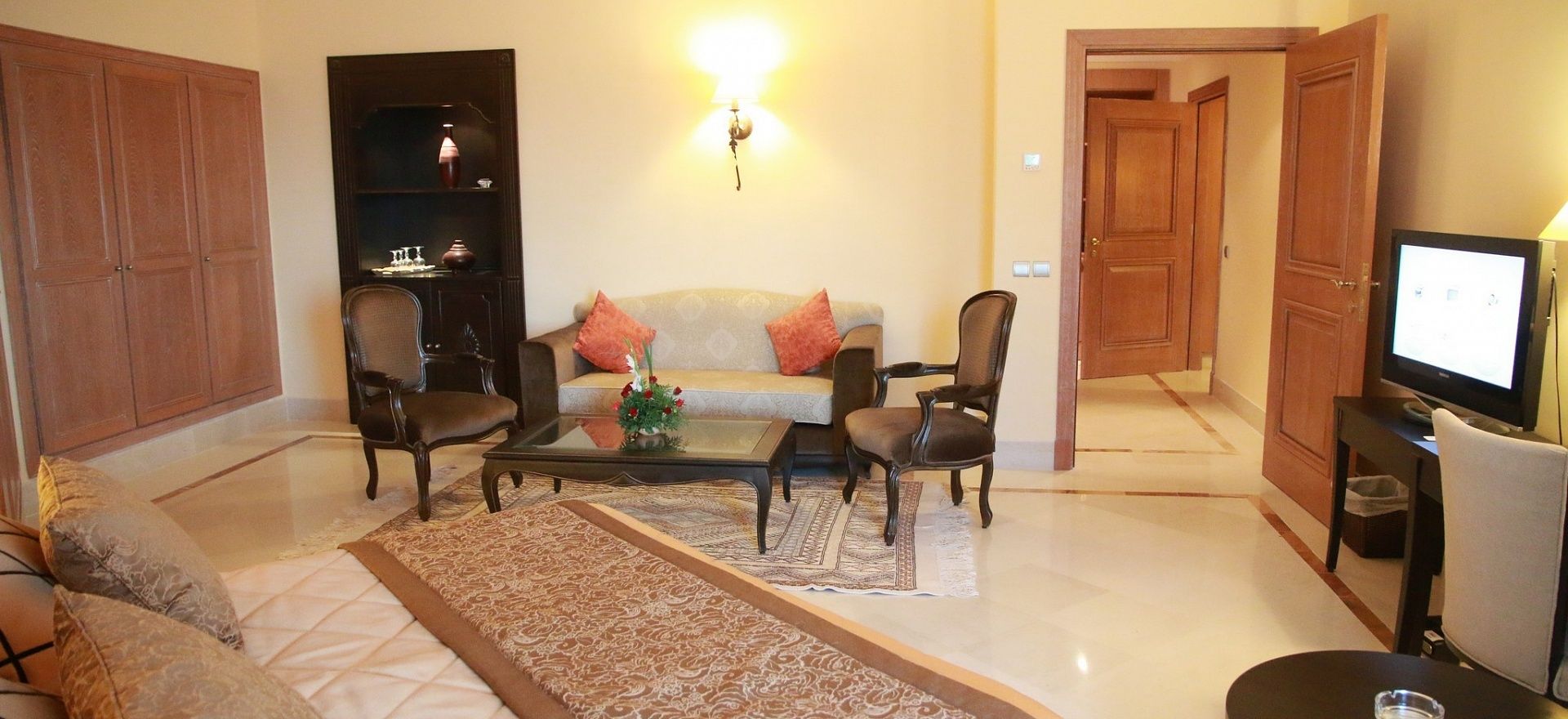 Una sala de estar con un sofá, dos sillones, una mesa de centro, un televisor y una estantería.