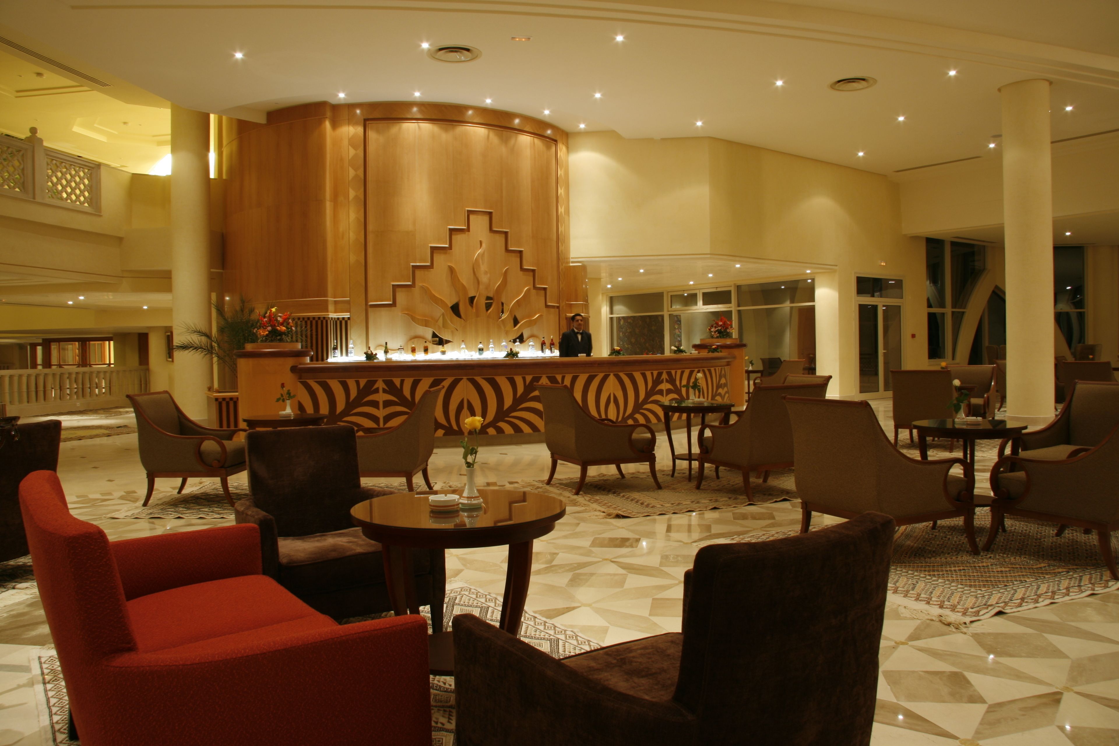 A lobby with a reception desk, multiple seating areas, and a decorative wall.