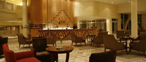 A lobby with a reception desk, multiple seating areas, and a decorative wall.