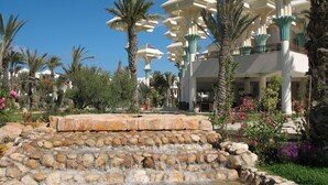 Ein Resort mit einer mehrstufigen Wasseranlage, Palmen und einem mehrstöckigen Gebäude in Weiß und Grün.
