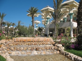 Una piscina techada, una piscina al aire libre, sombrillas